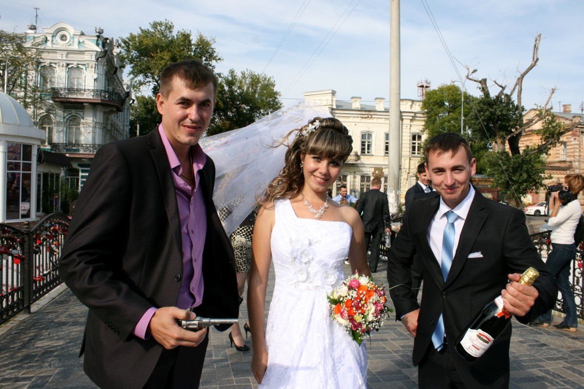Awkward wedding photo session: the bride surrounded with friends holding a gun and a champagne bottle Awkward wedding photo session: the bride surrounded with friends holding a gun and a champagne bottle