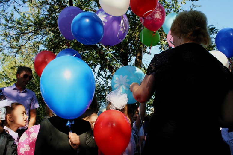 First year school boy is hiding behind a balloon